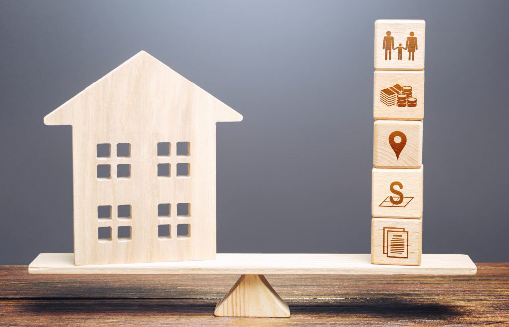 L’estimation d'un bien immobilier repose sur plusieurs critères objectifs : image d'une balance en bois avec d'un côté une façade de maison en bois et de l'autre des dés avec des images des critères sur lesquels repose l'estimation immobilière